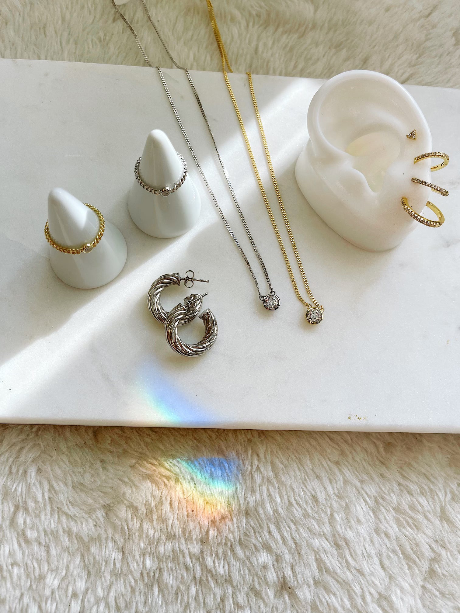 Jewelry including earrings and a necklace on a white surface with a soft background